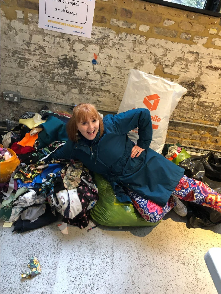 Yvette lying next to bags of fabric and textile waste saved from landfill after a sewing swap
